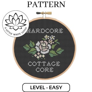Puede incluir: Un patrón de punto de cruz en blanco y negro con un diseño floral y el texto "HARDCORE COTTAGE CORE". El patrón está enmarcado en un aro de madera.