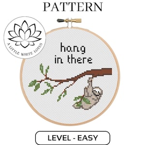 Pode incluir: Padrão de ponto cruz com um bicho-preguiça pendurado em um galho com o texto "hang in there". O padrão é classificado como "fácil" e é compatível com o software Pattern Keeper.
