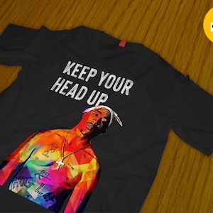 May include: Black t-shirt with a colorful illustration of rapper Tupac Shakur and the text "Keep Your Head Up".