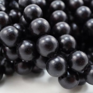 May include: A close-up of a strand of black wooden beads. The beads are round and smooth, and they have a glossy finish.