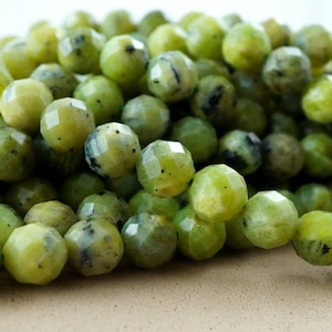 May include: A strand of green gemstone beads with a faceted finish. The beads are round and have a speckled appearance.