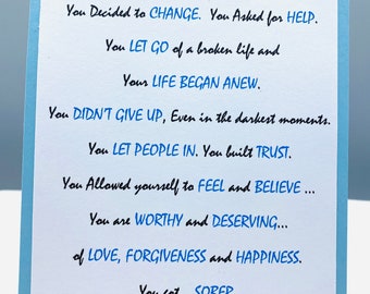 May include: A blue card with a message of encouragement and support for someone who has gotten sober. The message reads: "With courage and strength, you decided to change. You asked for help. You let go of a broken life and your life began anew. You didn't give up, even in the darkest moments. You let people in. You built trust. You allowed yourself to feel and believe... You are worthy and deserving... of love, forgiveness and happiness. You got... sober."