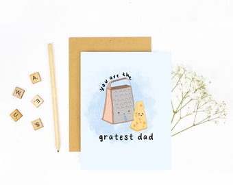 May include: A blue and white card with a cartoon illustration of a grater and a block of cheese. The grater and cheese have faces and the text "You are the greatest dad" is written below the illustration.