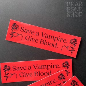 May include: Three red stickers with black text and a black rose design. The text on the stickers reads "Save a Vampire. Give Blood."