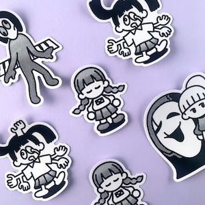 以下が含まれることがあります： 白黒の漫画キャラクターが描かれたステッカーが5枚。ステッカーは薄い紫色の背景に貼られています。キャラクターは、ピアノを弾いている棒人間、ツインテールとドレスを着た女の子、ツインテールとドレスを着た女の子、ツインテールとドレスを着た女の子、ツインテールとドレスを着た女の子です。