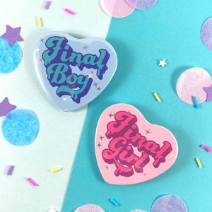 以下が含まれることがあります： レトロなフォントで「ファイナルボーイ」と「ファイナルガール」と書かれたハート型のピン2つ。ピンは青とピンクで、キラキラとしたアクセントが施されています。