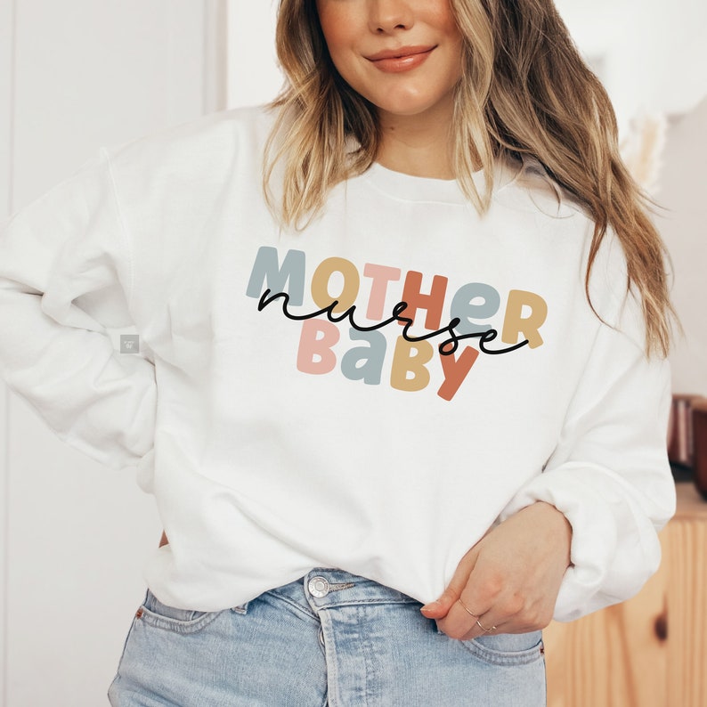 Pode incluir: Camisola branca com o texto "MOTHER nurse BABY" em letras coloridas. As letras est&atilde;o em um esquema de cores arco-&iacute;ris.