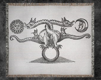 Puede incluir: Una ilustración en blanco y negro de un dragón de tres cabezas que sostiene un círculo en sus garras. El dragón está rodeado por un sol y una luna creciente.