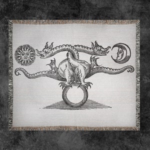 May include: A black and white illustration of a three-headed dragon holding a circle in its claws. The dragon is surrounded by a sun and a crescent moon.