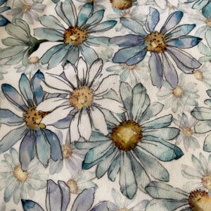 May include: A fabric with a repeating pattern of watercolor-style daisies. The flowers have white petals with blue and green tips, surrounding yellow centers. The background is a soft white, creating a delicate, floral design.