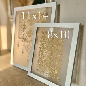 K&ouml;nnte beinhalten: Zwei wei&szlig;e Bilderrahmen mit goldenen geometrischen Mustern im Inneren. Der gr&ouml;&szlig;ere Rahmen ist mit "11x14" beschriftet und der kleinere Rahmen mit "8x10".