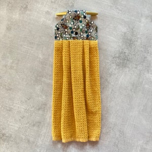 May include: A yellow waffle weave kitchen towel with a gray and white fabric bee print hanging loop.