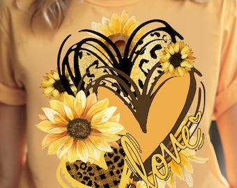 May include: A yellow t-shirt with a black and brown heart design featuring sunflowers and leopard print. The word "love" is written in a cursive font inside the heart.