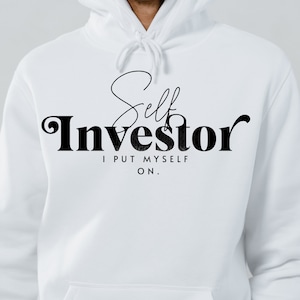 May include: White hoodie with black text that reads "Self Investor I PUT MYSELF ON."