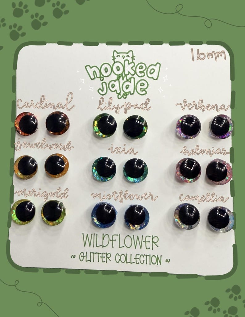 May include: A display card featuring a collection of 16mm glitter eyes from the "Wildflower Glitter Collection." The eyes are in various colors, including red, green, purple, and blue, with names like "Cardinal," "Lilypad," and "Verbena."