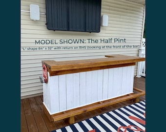 May include: A white and brown wooden bar with a white countertop and a brown base. The bar is 84 inches long and 32 inches wide. The bar is in an outdoor setting with a striped rug underneath.