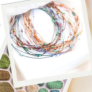 May include: A collection of colorful beaded bracelets, each with a thin cord and small, vibrant beads in various colors. The bracelets are arranged in a circular pattern on a white surface, suggesting a jewelry display.