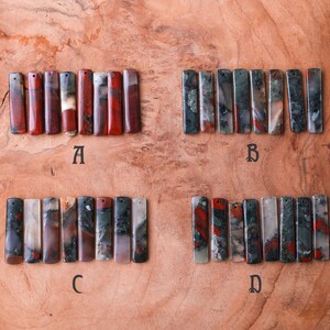 May include: Four sets of rectangular gemstone pendants, each with a hole for stringing. The pendants are in shades of red, green, gray, and white. The letter A, B, C, and D are below each set of pendants.