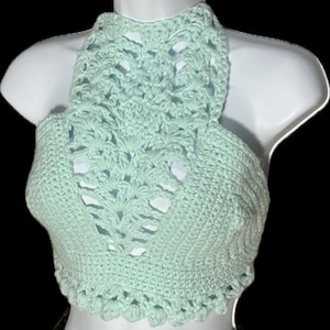 May include: A light green crocheted halter top with a delicate openwork design. The top is cropped and has a scalloped hem.