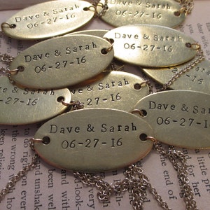 May include: A close-up of several oval-shaped brass tags with the text "Dave & Sarah 06-27-16" engraved on them. The tags are connected by silver chains.