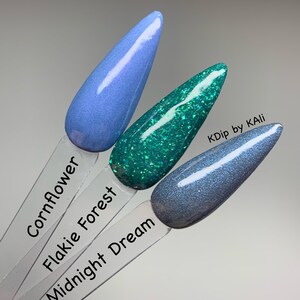 May include: Three nail polish swatches in Cornflower, Flakie Forest, and Midnight Dream. Cornflower is a light blue, Flakie Forest is a glittery teal, and Midnight Dream is a dark blue with shimmer. The text "KDip by KAli" is visible.