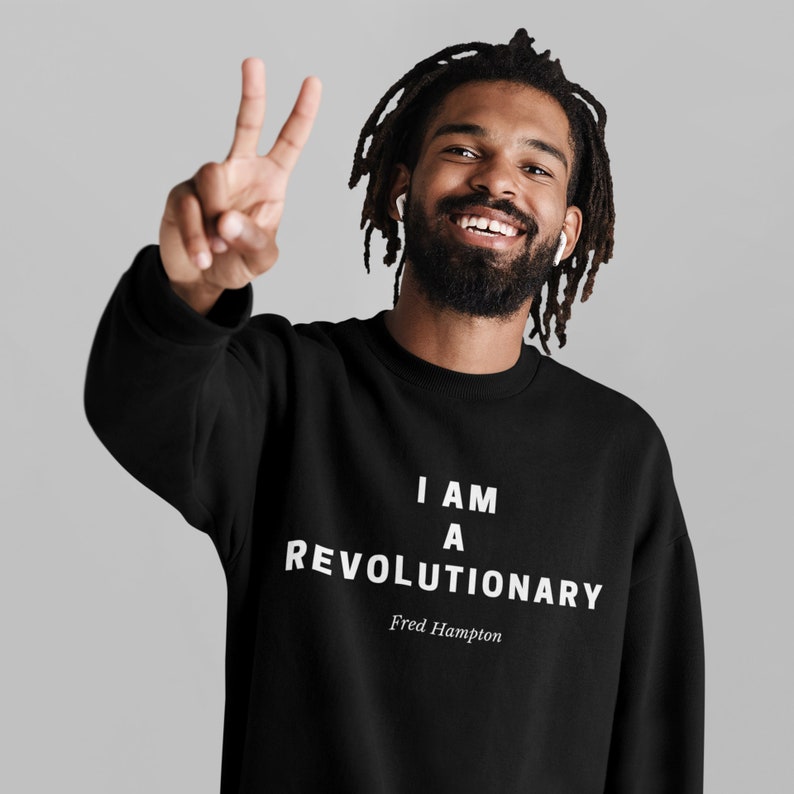 May include: A black sweatshirt with the text "I am a revolutionary" and "Fred Hampton" printed in white.