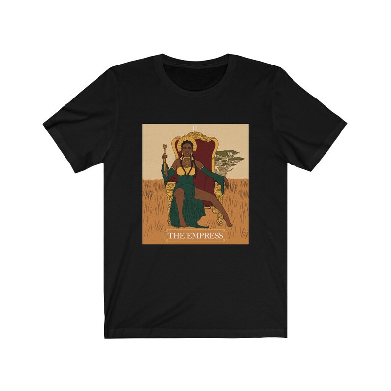May include: Black t-shirt with a graphic of the Empress tarot card featuring a Black woman in a green dress sitting on a throne. The card is labeled "III THE EMPRESS".