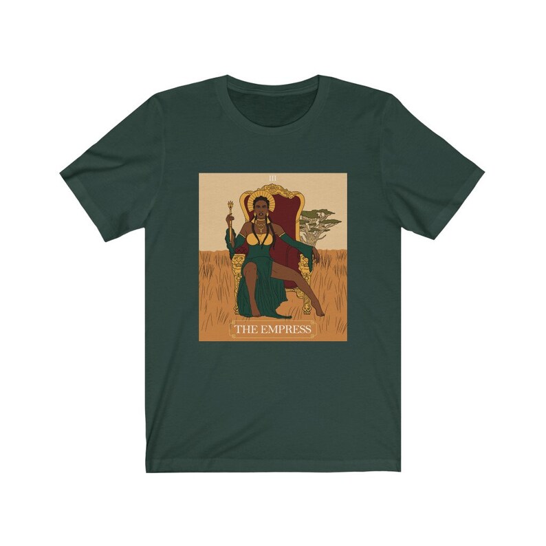 May include: A green t-shirt with a graphic of the Empress tarot card. The Empress is a black woman sitting on a throne with a crown and a scepter. The card is surrounded by a gold frame and the text "THE EMPRESS" is printed below the image.