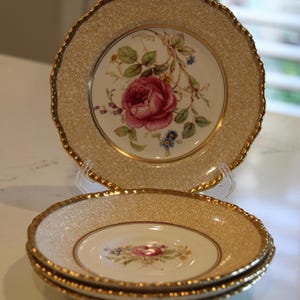 May include: Three vintage teacups with a gold rim and a floral pattern. The cups are stacked on top of each other.