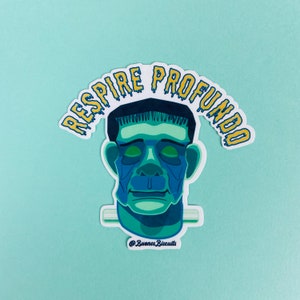 May include: A sticker featuring a stylized illustration of Frankenstein's monster in shades of blue and green. The text "RESPIRA PROFUNDO" in yellow and blue arcs above the monster's head. The sticker has a white border and a light blue background.