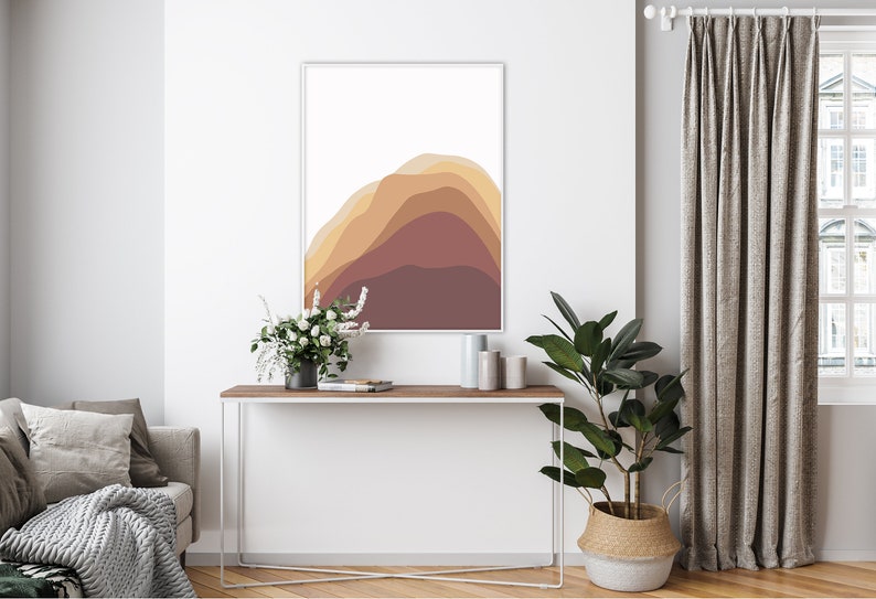 Puede incluir: Una impresi&oacute;n art&iacute;stica abstracta enmarcada con formas en capas en tonos marrones y naranjas. La obra de arte cuelga sobre una consola de madera con un marco de metal blanco. Una planta en maceta y flores a&ntilde;aden un toque natural a la habitaci&oacute;n.