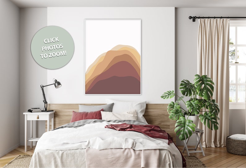 Puede incluir: Una impresi&oacute;n art&iacute;stica abstracta enmarcada con formas en capas en tonos marr&oacute;n, beige y burdeos. La obra de arte cuelga sobre una cama con ropa de cama blanca, almohadas rojas y un cabecero de madera. Una planta verde est&aacute; cerca de la ventana.