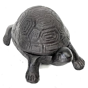 May include: A dark gray cast iron turtle figurine. The turtle has a textured shell and detailed legs and head. The figurine is a decorative item, likely for a home or garden.