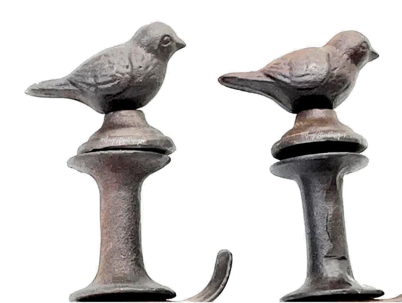 May include: Two cast iron bird-shaped decorative hooks. The birds are perched atop ornate, pedestal-style bases. The hooks are finished in a rustic, dark brown color, adding a vintage aesthetic. Ideal for hanging small items.
