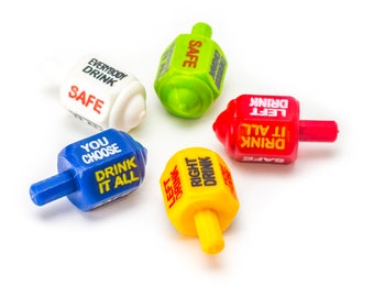 May include: Five colorful spinning tops with different drinking game instructions. The tops are red, yellow, blue, green, and white. The instructions include "Drink it all", "Safe", "Left Drink", "Right Drink", and "Everybody Drink".