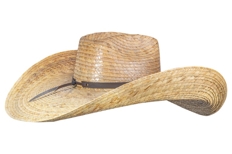 K&ouml;nnte beinhalten: Ein breitkrempiger Strohhut im Cowboy-Stil mit einem braunen Lederband. Der Hut ist aus geflochtenem Stroh gefertigt und hat eine leicht spitze Krone.