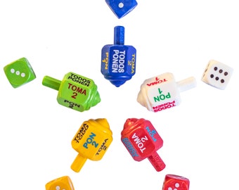 May include: A set of six colorful spinning tops with the words "Todos Ponen" and "Toma" on them. There are also six dice with different numbers of dots on them.