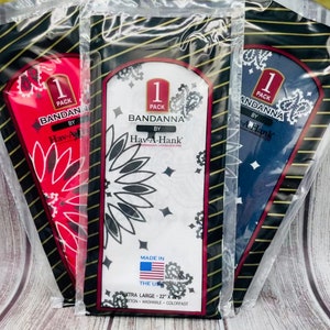 May include: Three packages of bandanas, each with a different color bandana inside. The bandanas are red, white, and blue. The packages are labeled "1 Pack Bandanna by Hav-A-Hank" and "Made in the USA".