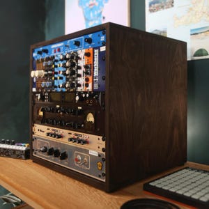 Op de afbeelding: Een rackbehuizing van donker hout met meerdere audioverwerkingsmodules. Het voorpaneel is voorzien van diverse knoppen, schakelaars en een ronde analoge meter. Labels bevatten onder andere Spectrum, Workhorse en Chroma.