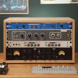 May include: A wooden rack containing four audio processing units: a blue DeltaLab Effectron II ADM 1020, a gray Coil CA70s, a white Chroma+ unit, and a black dual-channel 1176 custom compressor with two analog VU meters.