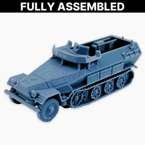 May include: A blue model of a military half-track vehicle, fully assembled. The model features detailed tracks, wheels, and a cabin. The text "FULLY ASSEMBLED" is displayed at the top of the image.