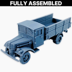 Może przedstawiać: W pełni zmontowany, niebieski model ciężarówki ze szczegółową kabiną i skrzynią ładunkową. Ciężarówka ma klasyczny design z widocznymi kołami, przednim zderzakiem i tekstem "FULLY ASSEMBLED" u góry.