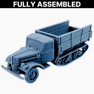 May include: A fully assembled, light blue model of a tracked truck. The model has a detailed cab, cargo bed, and track system. The text "FULLY ASSEMBLED" is printed in white at the top. This model is likely for collectors or hobbyists, and is a miniature.