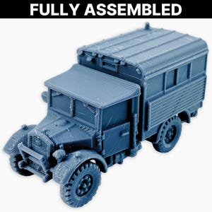 May include: A fully assembled, blue-grey model of a vintage military truck. The truck features a detailed cab, cargo area, and large tires. The text "FULLY ASSEMBLED" is printed in bold white letters at the top of the image.