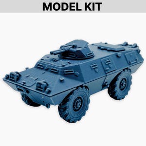 Puede incluir: Maqueta azul de un vehículo blindado con torreta y ruedas grandes. El texto "MODEL KIT" está en la parte superior de la imagen. El vehículo tiene un diseño detallado y está sobre un fondo blanco.