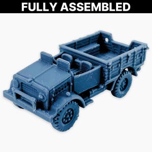 May include: A blue miniature truck with a detailed design. The truck has a cab with two seats, a cargo bed, and four wheels. The text "FULLY ASSEMBLED" is at the top of the image. This model is likely for hobbyists or collectors.