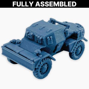 Può includere: Un modello blu completamente assemblato di un veicolo militare. Il modello presenta dettagli come ruote, un paraurti anteriore e una struttura superiore. Il testo "FULLY ASSEMBLED" è visualizzato sopra il veicolo.