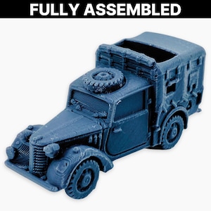 May include: A blue model of a vintage military truck, fully assembled. The truck features a spare tyre on the roof and detailed elements such as headlights, a front grille, and side windows. The text "FULLY ASSEMBLED" is at the top of the image.