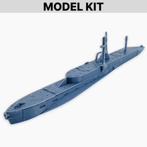 May include: A blue model submarine with detailed features, including a conning tower, deck hatches, and a forward gun. The model is labeled "MODEL KIT" at the top. The submarine is a detailed replica.