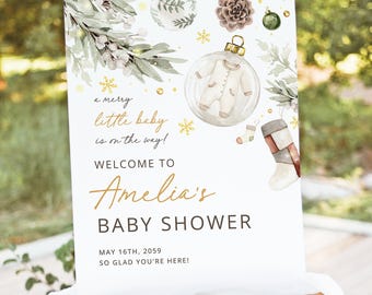 Può includere: Un cartello per il baby shower su un cavalletto. Il cartello presenta illustrazioni ad acquerello di verde, ornamenti e un body per neonati all'interno di una palla trasparente. Il testo recita "a merry little baby is on the way!" e "Welcome to Amelia's Baby Shower."